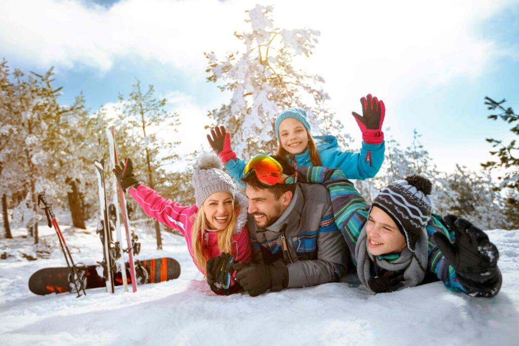 Lächelnde Familie genießt Winterurlaub in den Bergen im Schnee