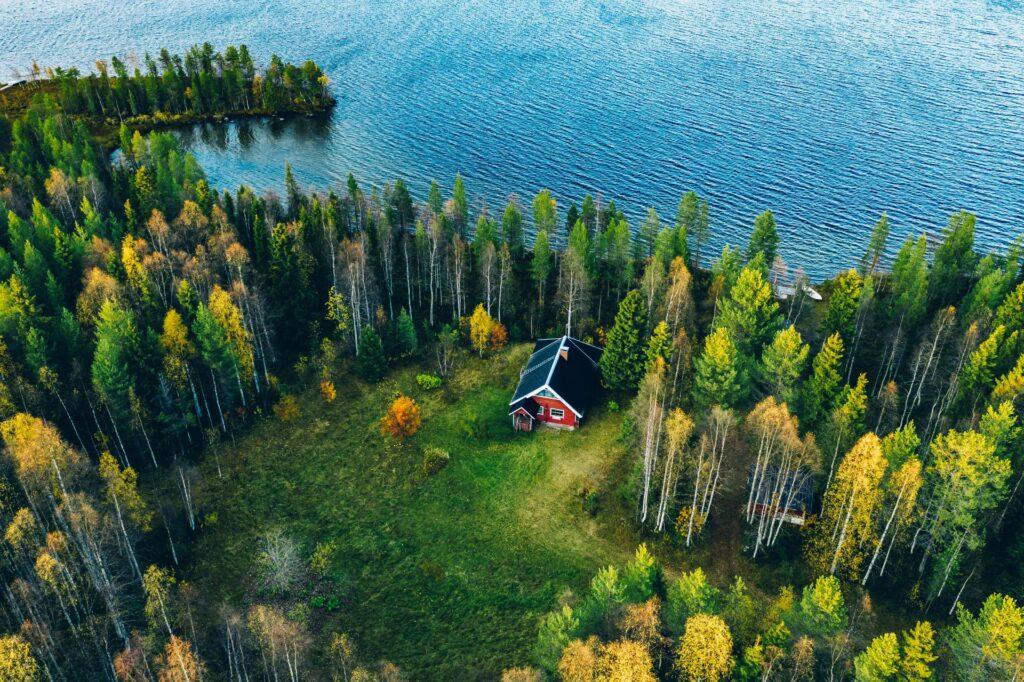 Rotes Ferienhaus im Bayerischen Wald, umgeben von herbstlicher Natur und einem See.