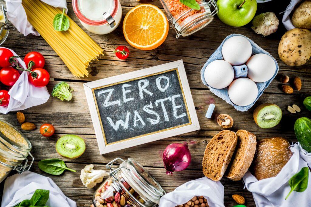 Ein Arrangement aus Bio-Lebensmitteln wie Gemüse, Obst und Eiern mit einer Tafel, auf der „Zero Waste“ geschrieben steht. Ideal zur Förderung von Nachhaltigkeit und umweltfreundlicher Ernährung.