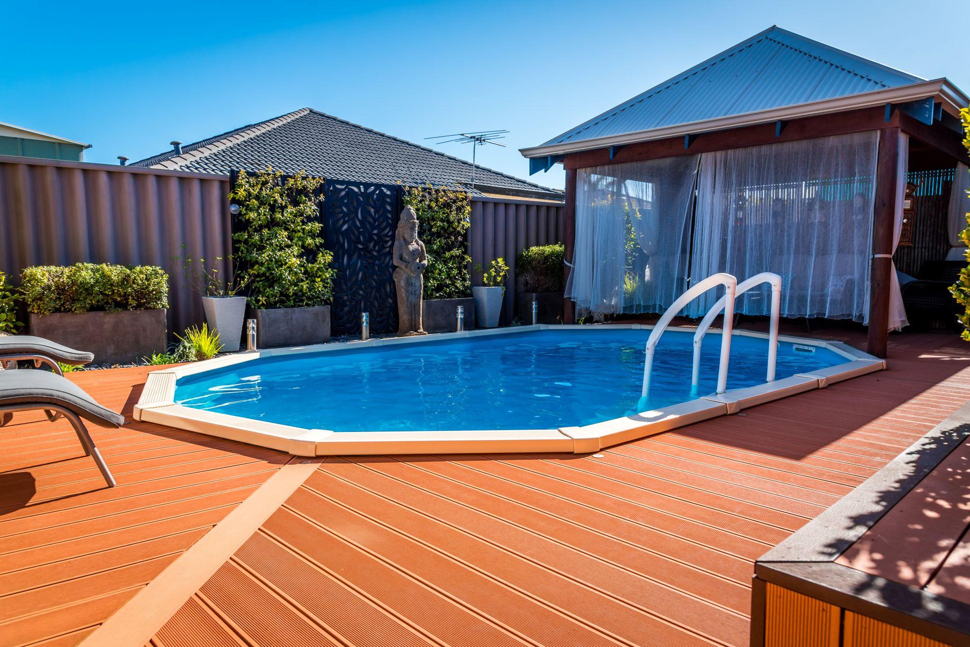 Stahlwandpool Oval mit Holzumrandung im Garten – Beispiel fuer platzsparende Poolgestaltung